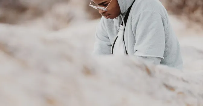 A young man with his head down sorrounded by white cloth looking contemplative