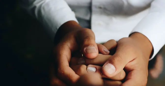 Hands holding and supporting another person's hands in a gesture of compassion